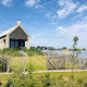 Modern tiny house Villa Oesterdam by the water at Oesterdam Resort, surrounded by greenery and blue sky.