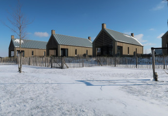 Moderne Tiny Houses bei Villa Oesterdam im Oesterdam Resort, Niederlande, umgeben von Schnee und Zaun.