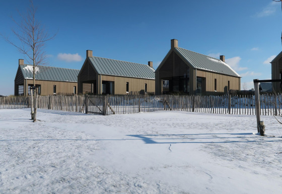 Moderne Tiny Houses bei Villa Oesterdam im Oesterdam Resort, Niederlande, umgeben von Schnee und Zaun.