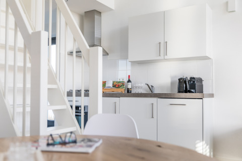 Cocina moderna y compacta con armarios blancos, encimera y escalera en Villa Oesterdam, Oesterdam Resort, Países Bajos.