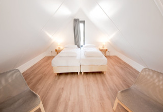 Schlafzimmer in der Villa Oesterdam mit zwei Einzelbetten, Holzboden und moderner Einrichtung, Oesterdam Resort.