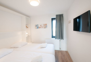 Dormitorio moderno y pequeño en Villa Oesterdam, Oesterdam Resort, Países Bajos, con dos camas y TV mural.