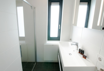 Bagno moderno e compatto nella Villa Oesterdam all’Oesterdam Resort, Paesi Bassi, con finestre luminose e design pulito.