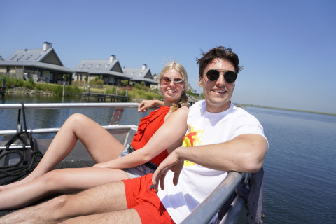 Una pareja se relaja en un bote frente a la tiny house Villa Oesterdam en Oesterdam Resort, Países Bajos.