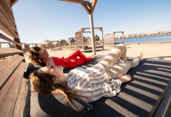 Zwei Frauen entspannen sich auf Liegen am Sandstrand der Villa Oesterdam im Oesterdam Resort, Niederlande.