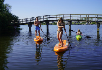 Menschen genießen Stand-Up-Paddling und Kajakfahren an der Villa Oesterdam, Oesterdam Resort, Niederlande.