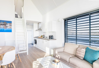 Salon moderne et lumineux de la tiny house Villa Oesterdam à Oesterdam Resort, Pays-Bas, avec cuisine.