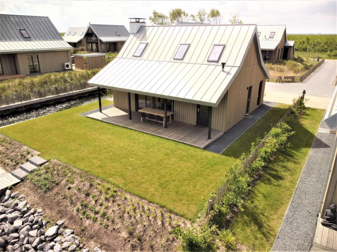 Villa Oesterdam Comfort Extra au Oesterdam Resort aux Pays-Bas, maison moderne avec terrasse et jardin vert.