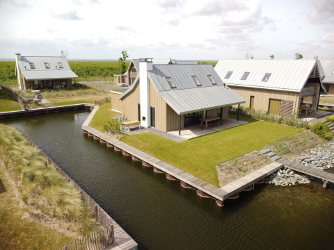 Villas modernas con césped y canales de agua en Oesterdam Resort, Países Bajos, vista aérea diurna.