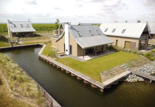 Villas modernas con césped y canales de agua en Oesterdam Resort, Países Bajos, vista aérea diurna.