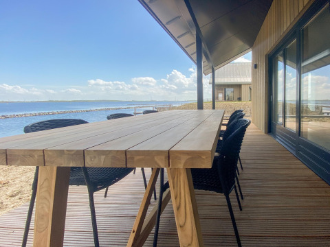 Terrasse der Villa Oesterdam Comfort Extra mit Holztisch und Wasserblick im Oesterdam Resort, Niederlande.