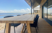 Terrasse der Villa Oesterdam Comfort Extra mit Holztisch und Wasserblick im Oesterdam Resort, Niederlande.