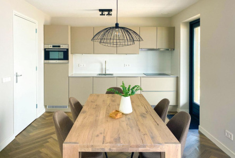 Cocina y comedor modernos en Villa Oesterdam Comfort Extra en Oesterdam Resort, Países Bajos, con mesa de madera.