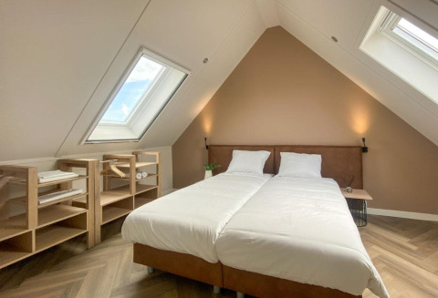 Dachzimmer mit zwei Betten, Holzregalen und Dachfenstern in der Villa Oesterdam Comfort Extra, Oesterdam Resort, Niederlande.