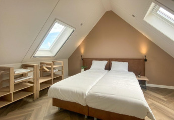 Dachzimmer mit zwei Betten, Holzregalen und Dachfenstern in der Villa Oesterdam Comfort Extra, Oesterdam Resort, Niederlande.