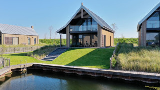 Moderne Villa Oesterdam Deluxe met schuine grasheuvel en privé water toegang in Oesterdam Resort, Nederland.