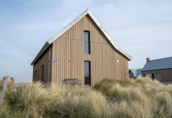 Petite maison Villa Oesterdam Deluxe au Oesterdam Resort aux Pays-Bas, entourée d’herbe et façade bois.