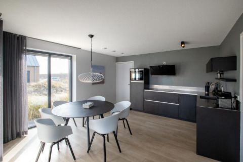 Sala de estar y cocina modernas en Villa Oesterdam Deluxe del Oesterdam Resort, Países Bajos, con luz natural.