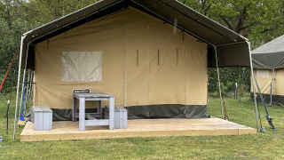 Safari tent XL en Holiday Park Duinhoeve, Países Bajos, con terraza de madera y mobiliario exterior.