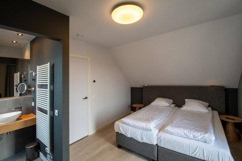 Dormitorio en Villa Oesterdam Deluxe en Oesterdam Resort con dos camas y baño moderno integrado.
