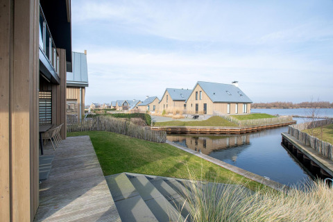 Vista de la Villa Oesterdam Deluxe en Oesterdam Resort, Países Bajos, con casas modernas junto al agua.