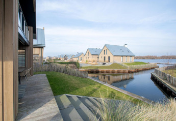 Vue sur la Villa Oesterdam Deluxe à Oesterdam Resort aux Pays-Bas, avec des cottages modernes au bord de l’eau.