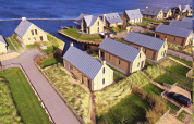 Luchtfoto van Villa Oesterdam bij Oesterdam Resort in Nederland, met moderne houten lodges aan het water.