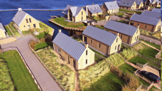 Luchtfoto van Villa Oesterdam bij Oesterdam Resort in Nederland, met moderne houten lodges aan het water.