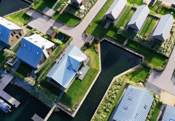 Aerial view of modern lodges with metal roofs and canals at Villa Oesterdam, Oesterdam Resort, Netherlands.