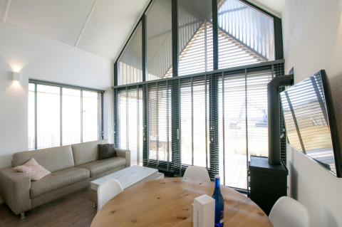 Lichte, moderne woonkamer in Villa Oesterdam op Oesterdam Resort, Nederland, met grote ramen en zetel.