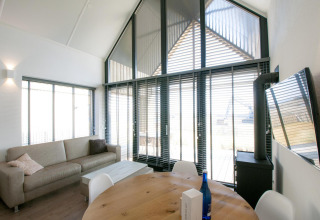 Lichte, moderne woonkamer in Villa Oesterdam op Oesterdam Resort, Nederland, met grote ramen en zetel.