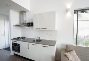 Kitchenette moderne à la Villa Oesterdam du Oesterdam Resort, avec évier, cuisinière et grande fenêtre.