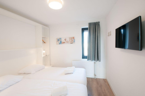 Luminoso dormitorio en Villa Oesterdam, Oesterdam Resort, Países Bajos, con dos camas, televisión y ventana.
