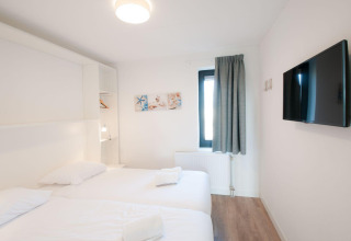 Lichte kamer in Villa Oesterdam, Oesterdam Resort, Nederland met twee bedden, tv en raam.