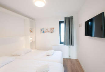 Chambre lumineuse à Villa Oesterdam, Oesterdam Resort, Pays-Bas avec deux lits, TV et fenêtre.