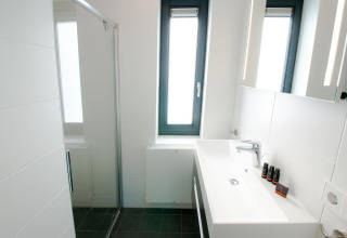 Baño moderno con lavabo grande, ducha de cristal y ventana en Villa Oesterdam, Oesterdam Resort, Países Bajos.