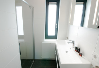 Moderne badeværelse med stor vask, glasbrusekabine og vindue på Villa Oesterdam, Oesterdam Resort, Holland.