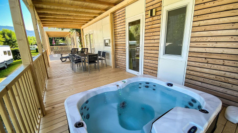 Træveranda med spabad og spiseplads ved Cottage Hot tub, Ossiacher See, Østrig, omgivet af natur.