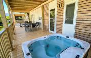 Porche de madera con jacuzzi y comedor en Cottage Hot tub, Ossiacher See, Austria, rodeado de naturaleza.