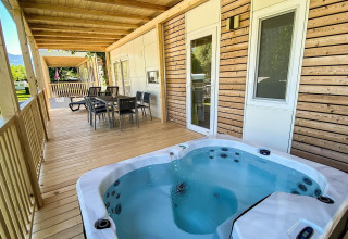 Træveranda med spabad og spiseplads ved Cottage Hot tub, Ossiacher See, Østrig, omgivet af natur.