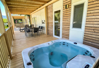 Træveranda med spabad og spiseplads ved Cottage Hot tub, Ossiacher See, Østrig, omgivet af natur.