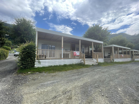 Gemütliche Cottages mit Veranda und Whirlpool am Ossiacher See in Österreich unter wolkigem Himmel.
