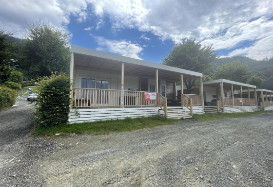 Gemütliche Cottages mit Veranda und Whirlpool am Ossiacher See in Österreich unter wolkigem Himmel.