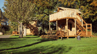 Safari-Glampingzelt Arriba im Resort de Parel in den Niederlanden mit Holzterrasse und Bäumen.