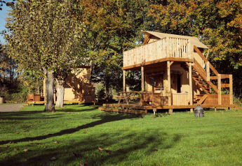 Tenda glamping Arriba al Resort de Parel nei Paesi Bassi, con terrazza in legno e alberi verdi.