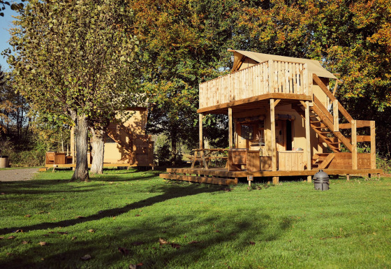 Safari-Glampingzelt Arriba im Resort de Parel in den Niederlanden mit Holzterrasse und Bäumen.