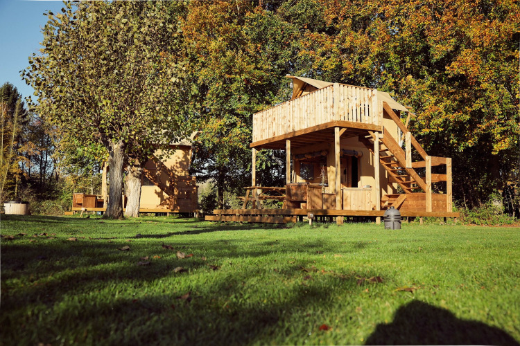Glampingtent Arriba, een safaritent bij Resort de Parel in Nederland, tussen bomen en grasvelden.
