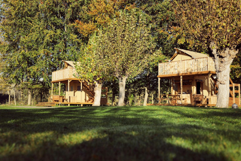 Dos tiendas glamping tipo safari en Resort de Parel, Países Bajos, rodeadas de césped y árboles verdes.