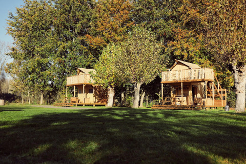 Deux tentes safari glamping avec terrasses en bois au Resort de Parel, entourées d’arbres aux Pays-Bas.