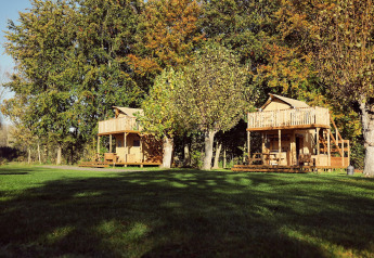 Twee glamping safaritenten met houten veranda’s bij Resort de Parel, omringd door bomen in Nederland.